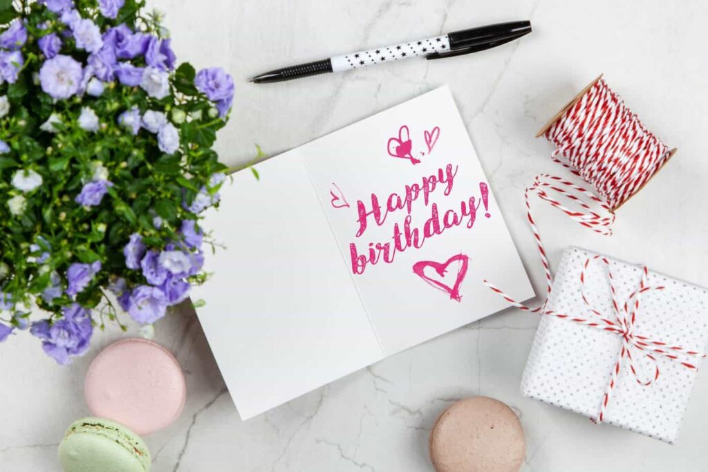 Happy birthday message on card with flowers, present, and macaroons