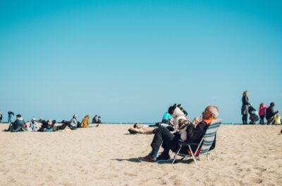 Man sitting in chair with dog at crowded beach
