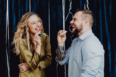 Two people laughing and blowing party horns