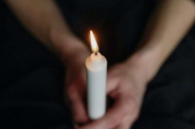 Person holding a single lit candle