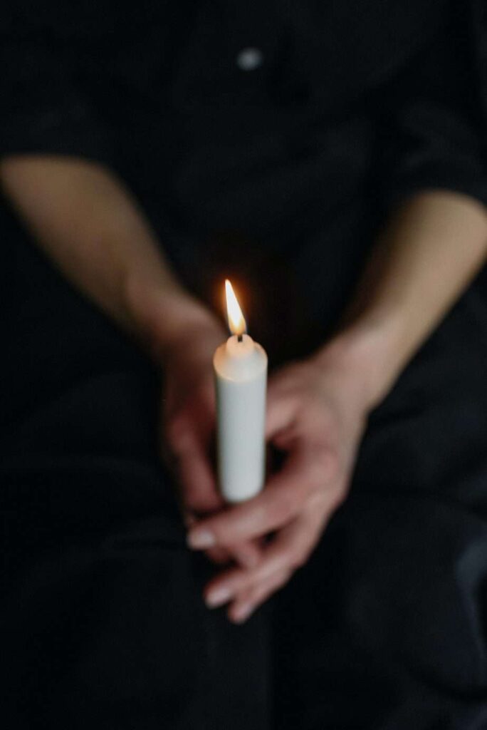 Person holding a single lit candle