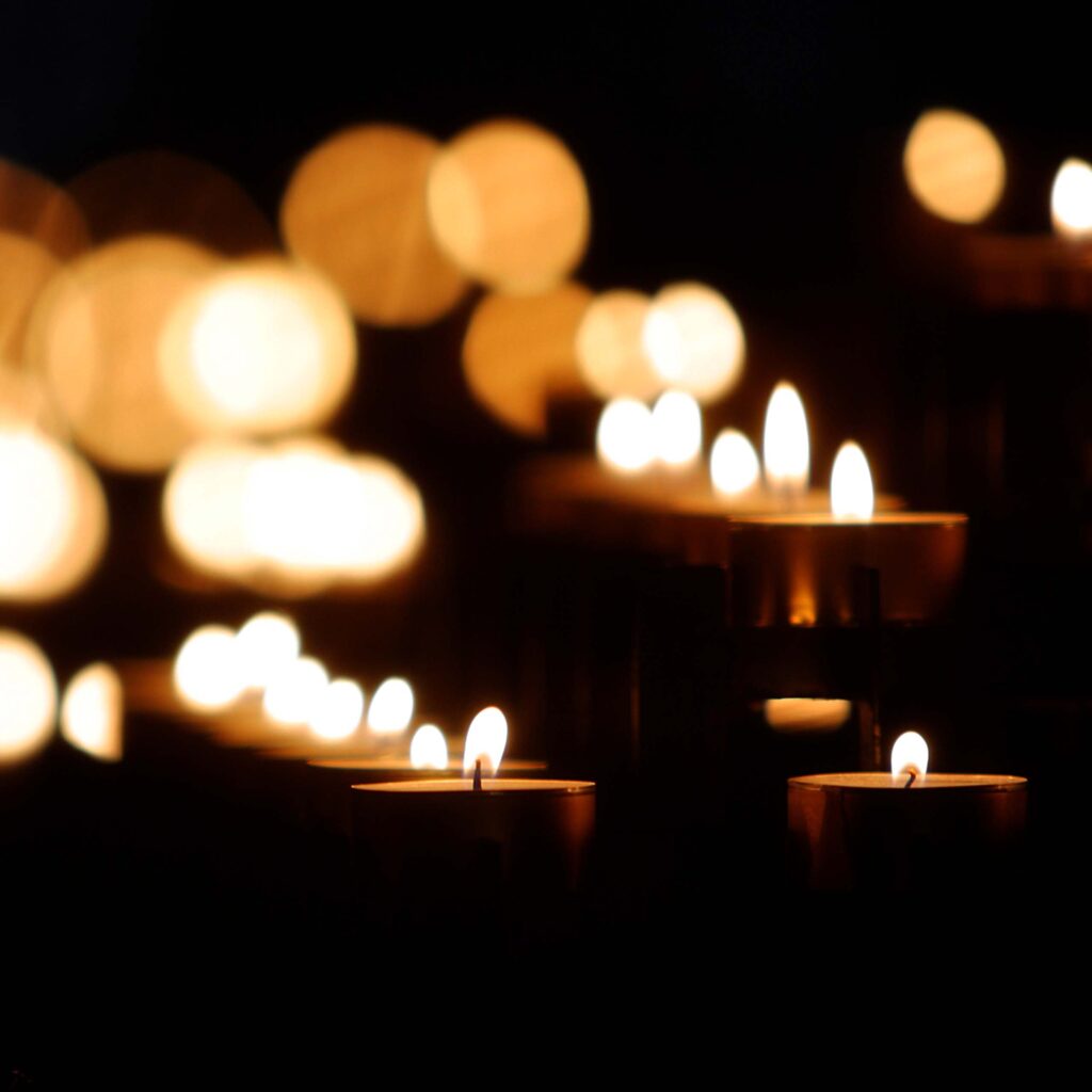 Votive candles burning in dark room