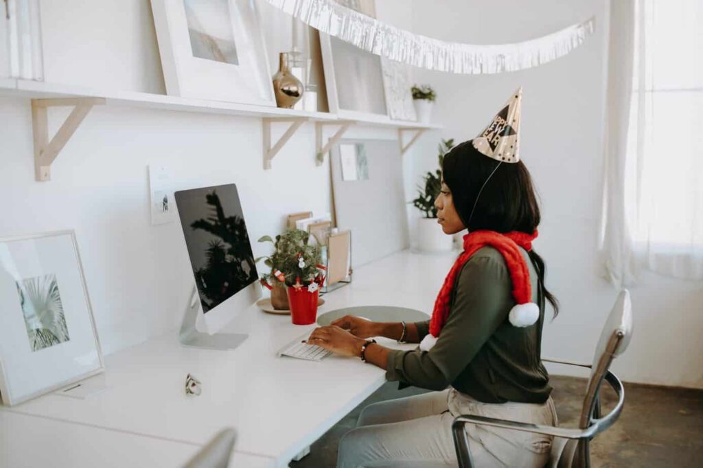 Woman in birthday hat working on desktop computer