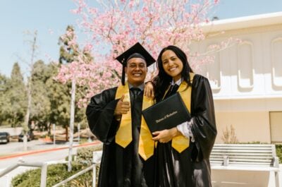 Two graduates smiling and posing with diploma