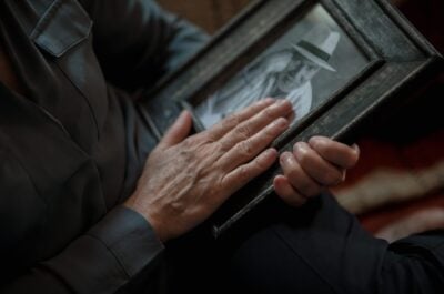 Hands held over photo with old man