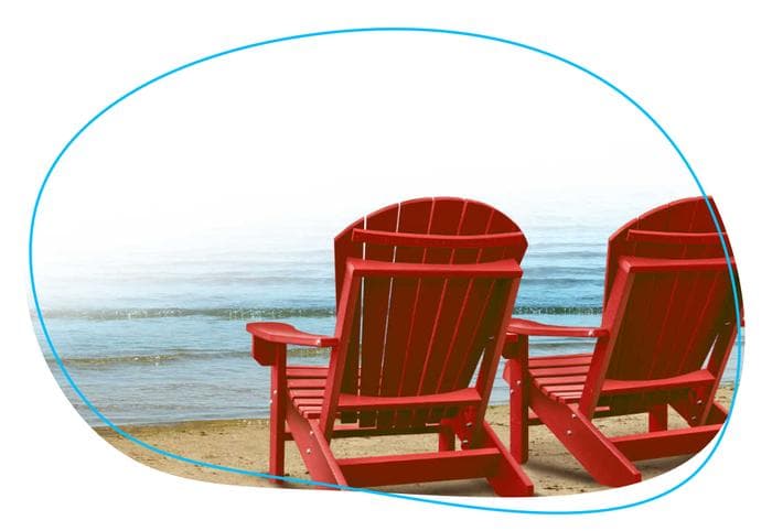 Two lawn chairs on the edge of the beach