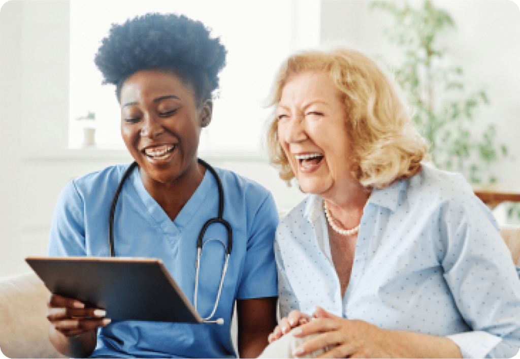 Healthcare worker holding tablet laughing with patient