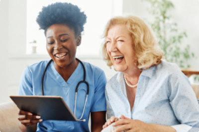 Healthcare worker holding tablet laughing with patient