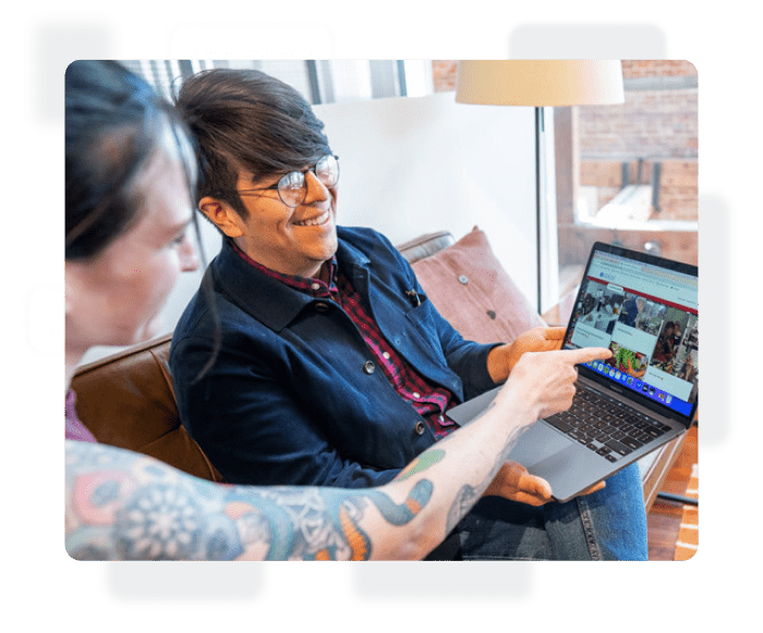 Two employees looking at Kudoboard on laptop