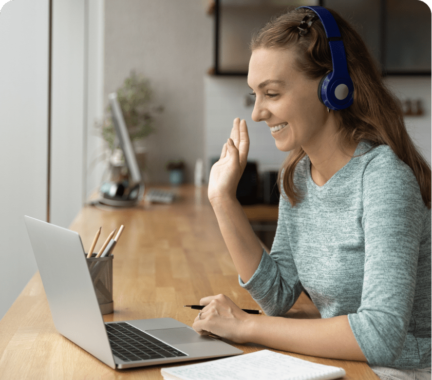 Woman smiling and waving to people on laptop