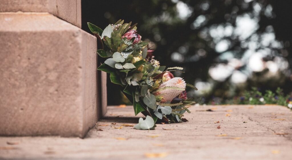 Floral wreath sitting on ground by gravestone