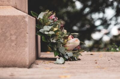 Floral wreath sitting on ground by gravestone