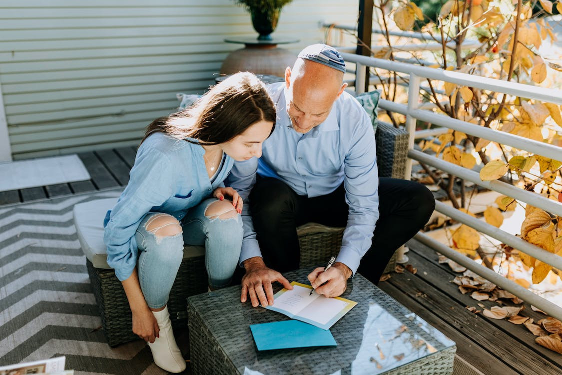 Two people sitting around small table signing a goodbye card