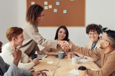 Coworkers shaking hands across table of peers