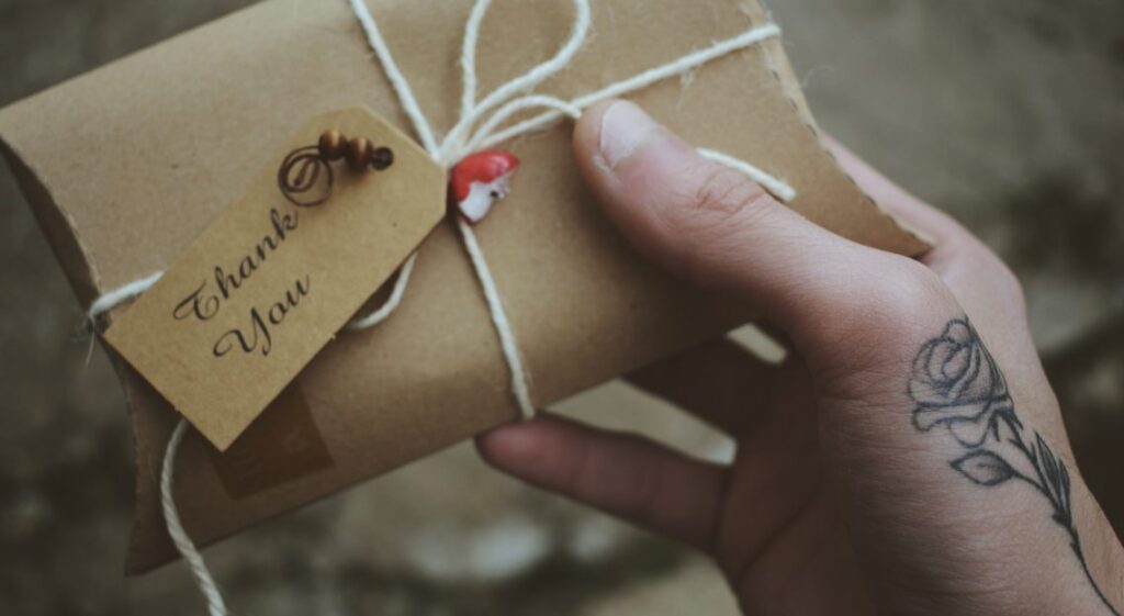 Hand holding an envelope with a thank you tag attached