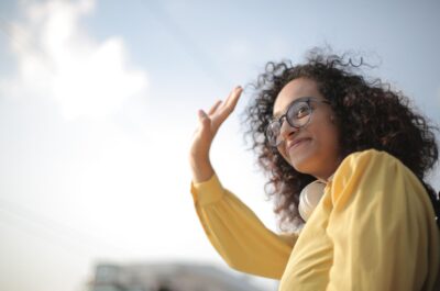 Person waving farewell with the sky behind them