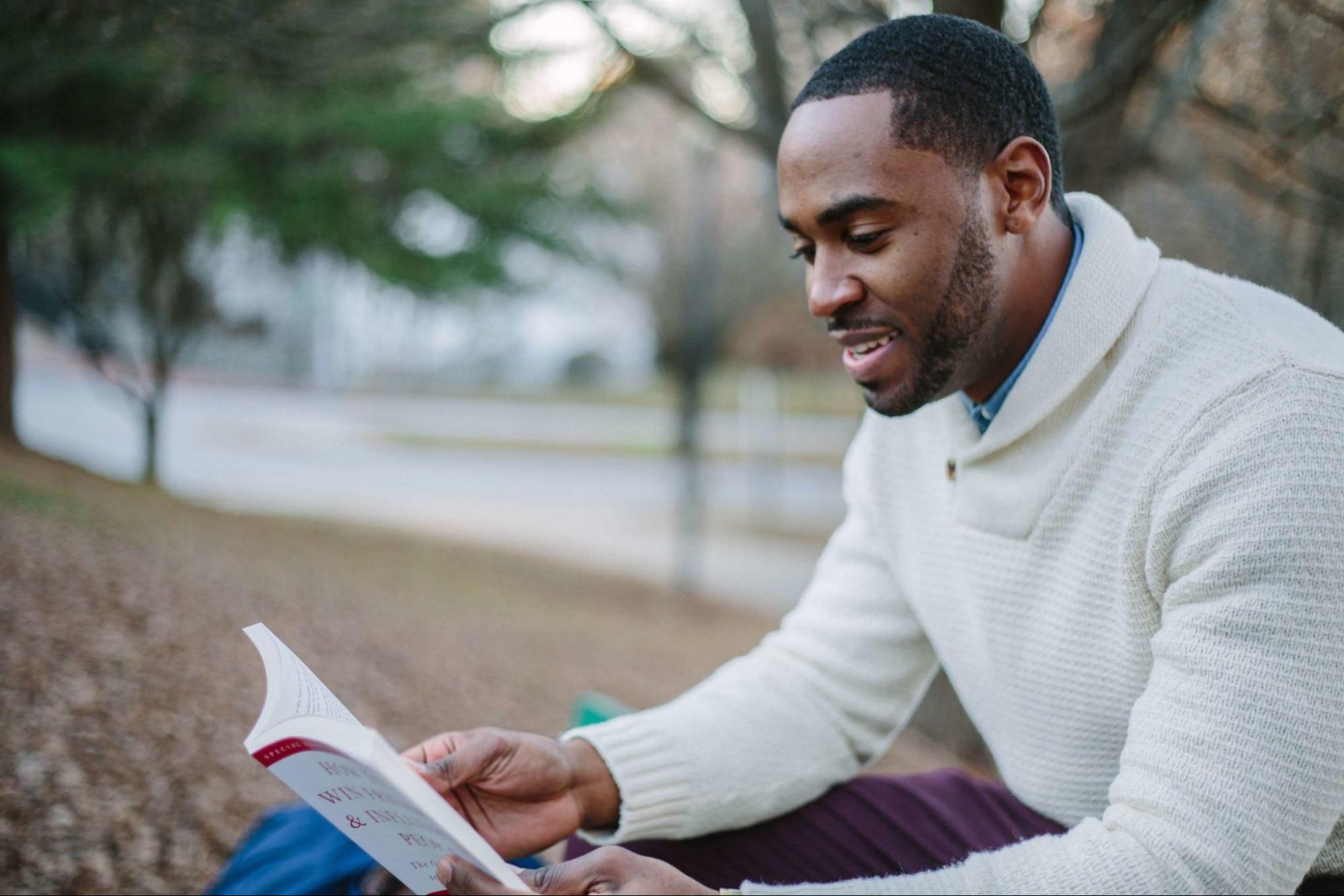 Man reading book while listening to audiobook