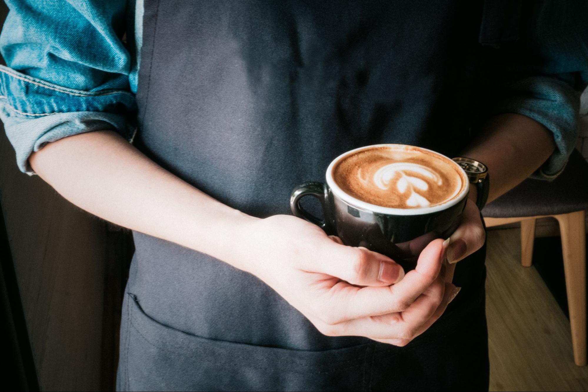 Local barista holding coffee cup