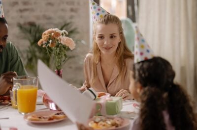 Woman wearing party hat at table with family