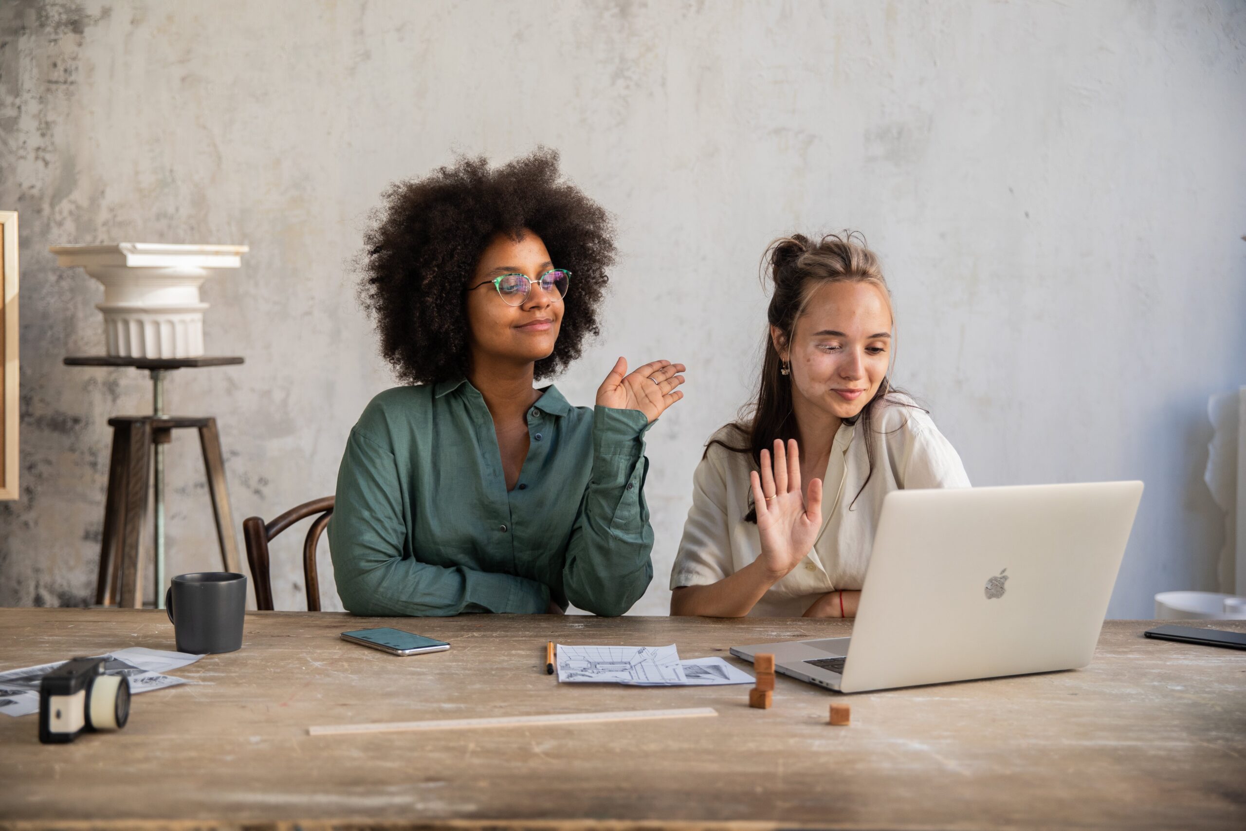 Two women waving goodbye to someone on laptop