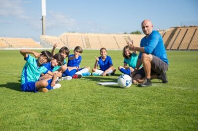 Soccer coach working with kids on field