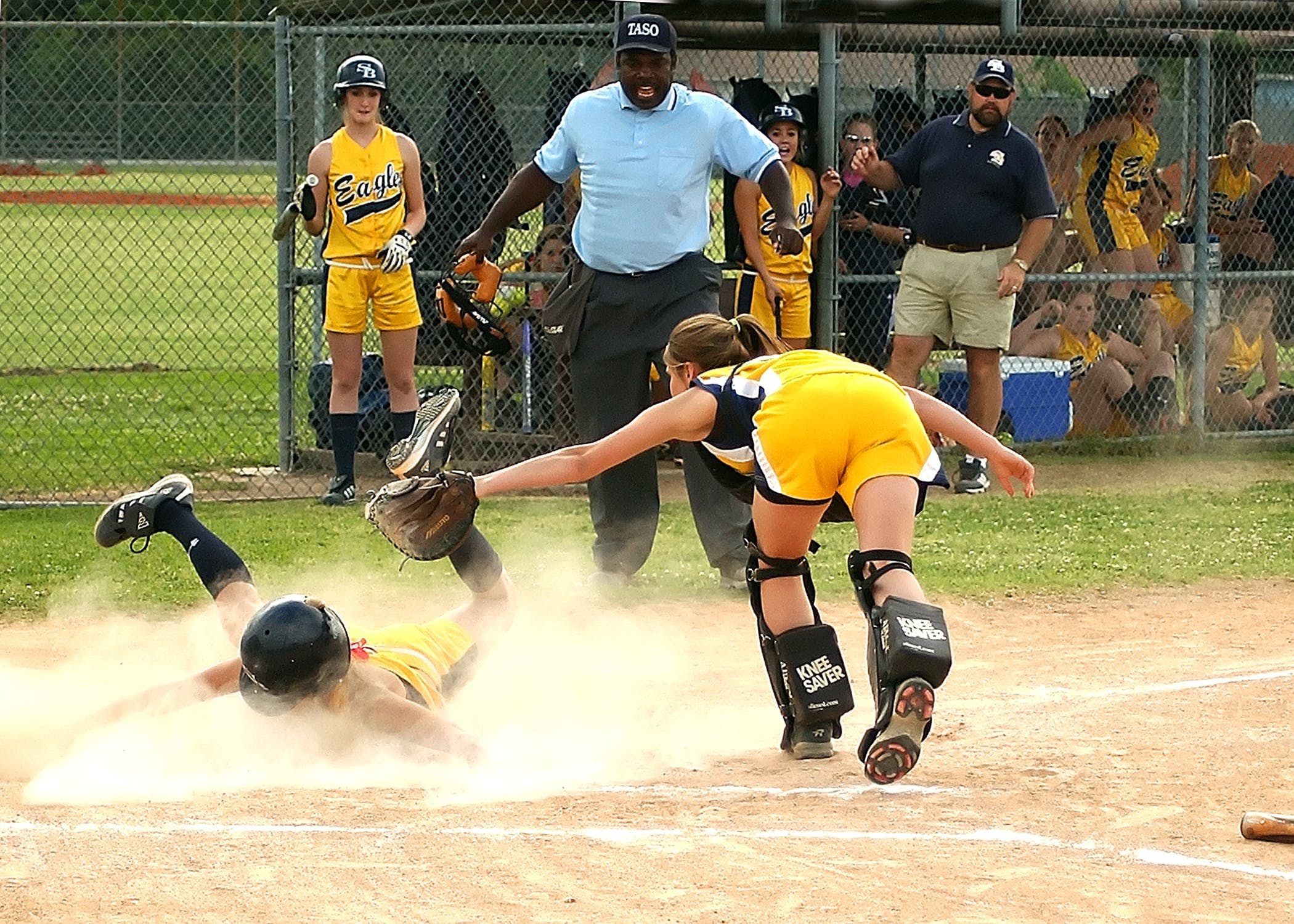 Softball player tagging girl out at plate
