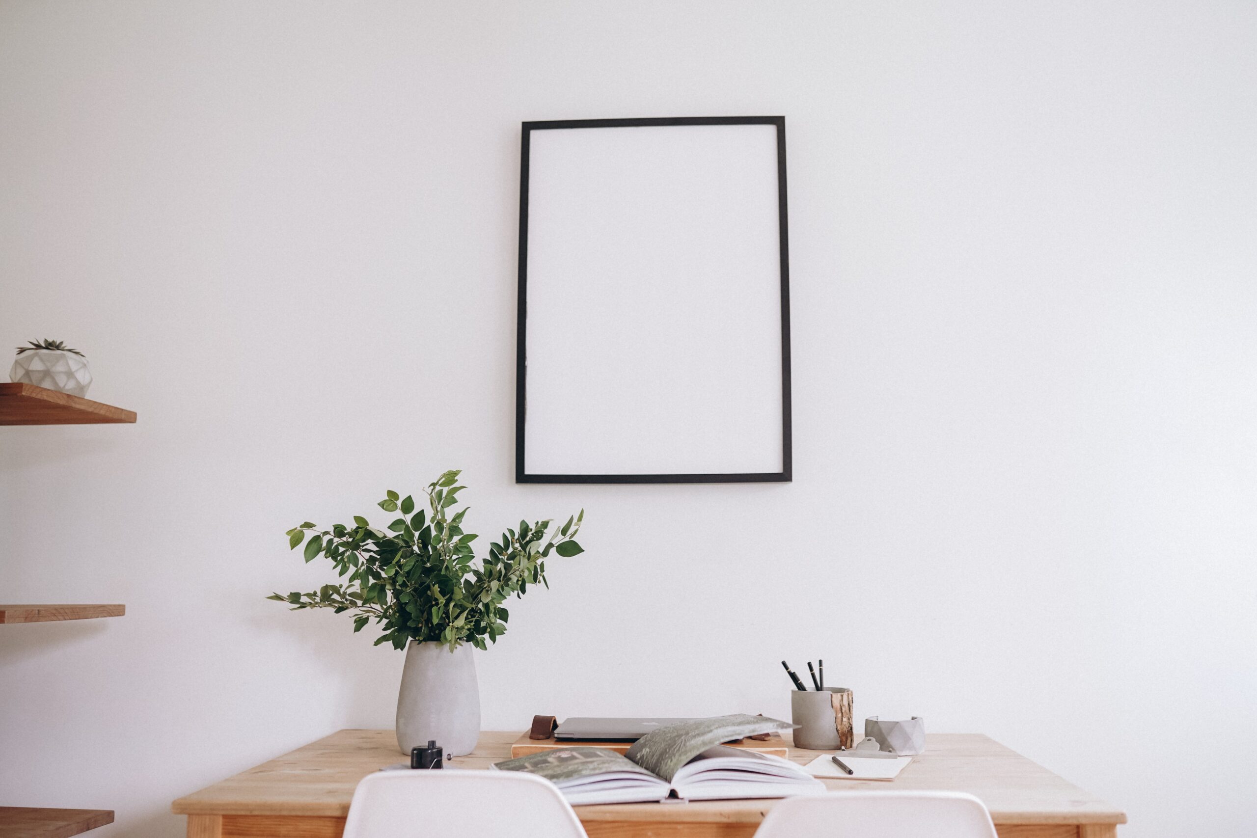 Empty poster frame in front of desk