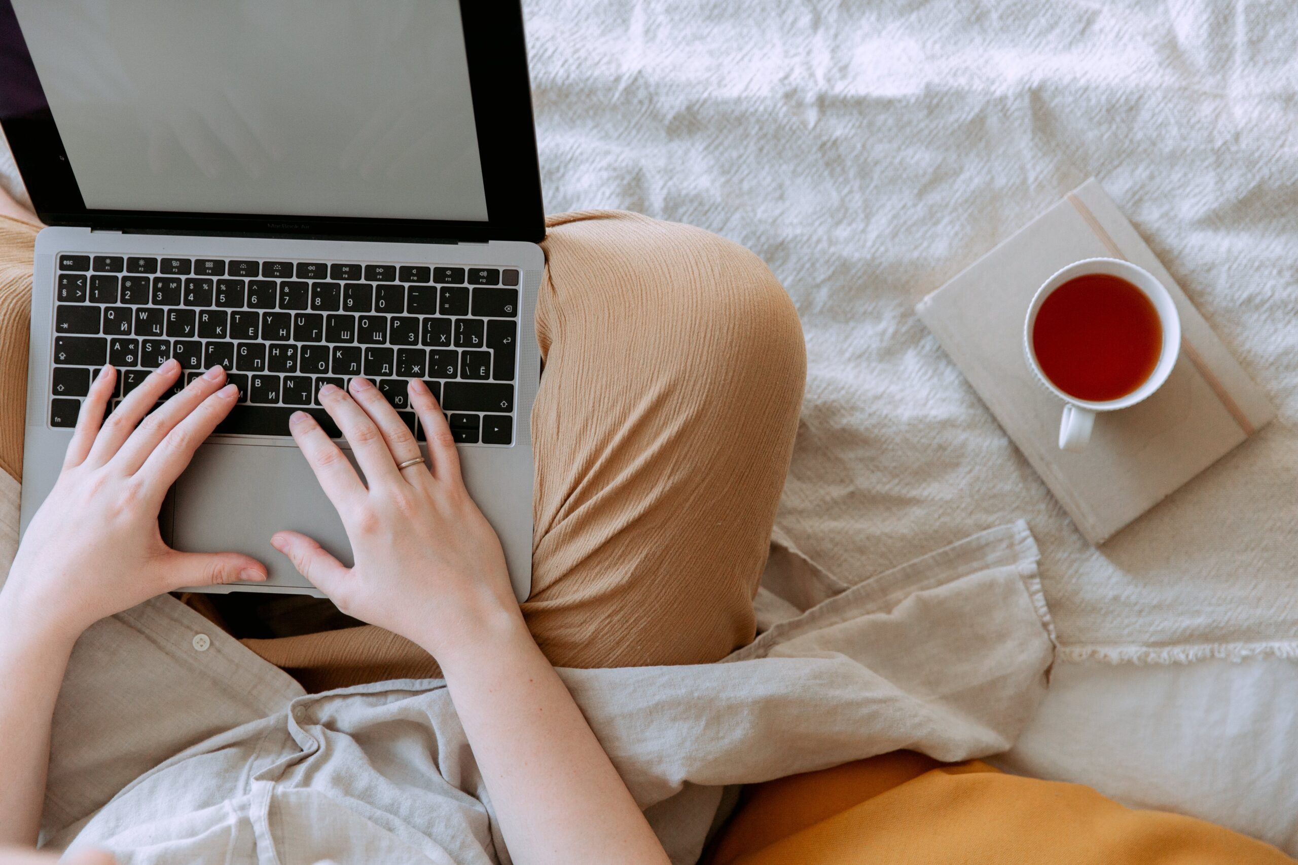 Person typing on laptop on bed