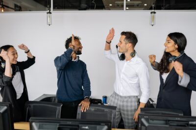 Two workers high-fiving in office