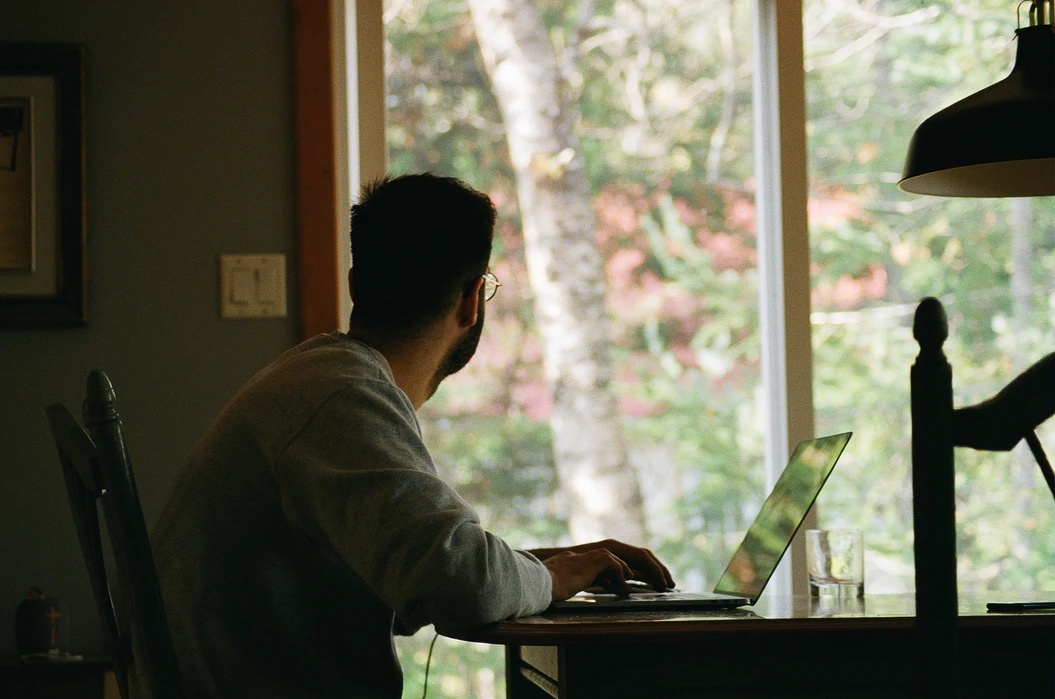 Person on laptop looking out window