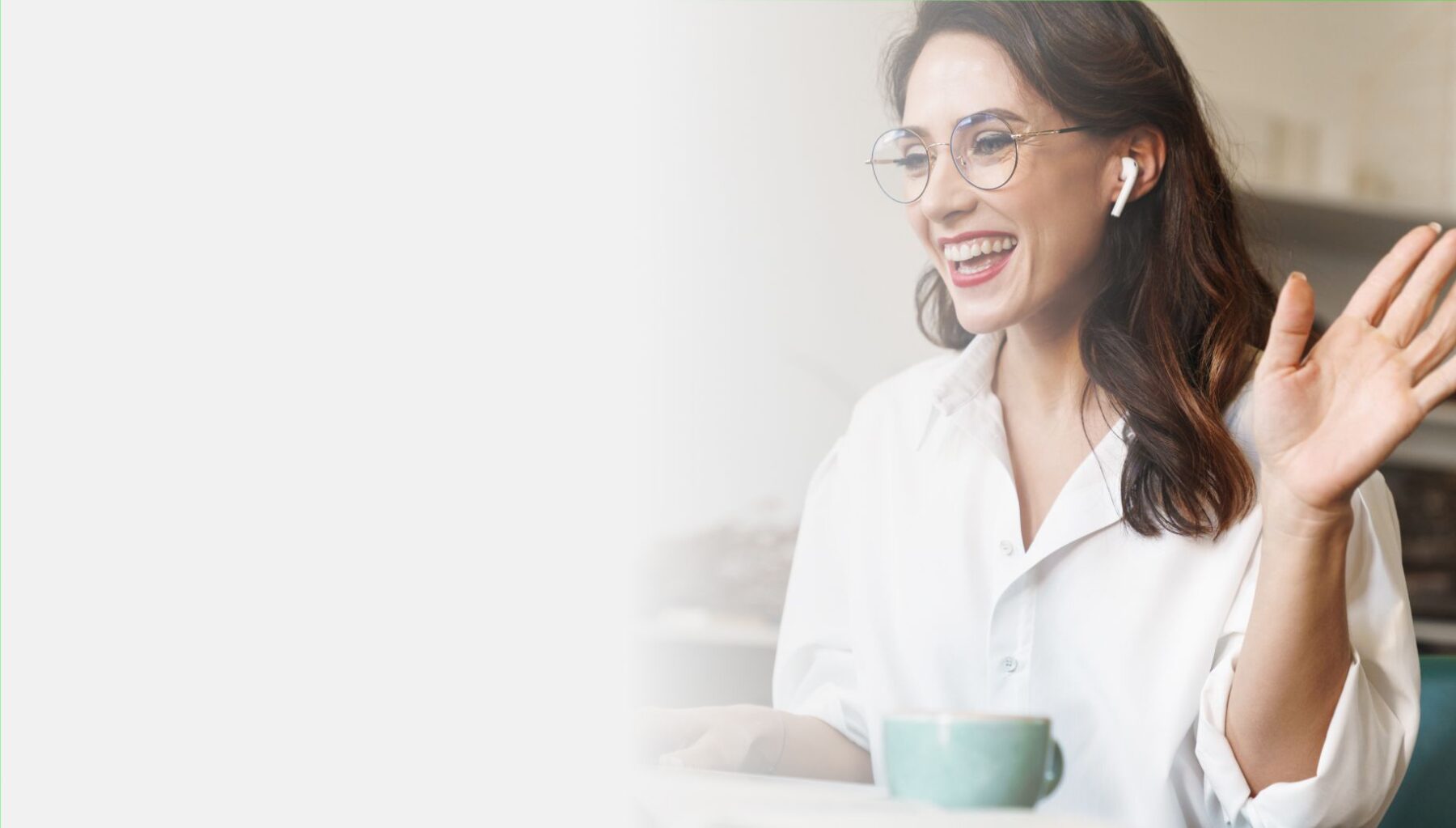 Woman with coffee waving hello to people on computer