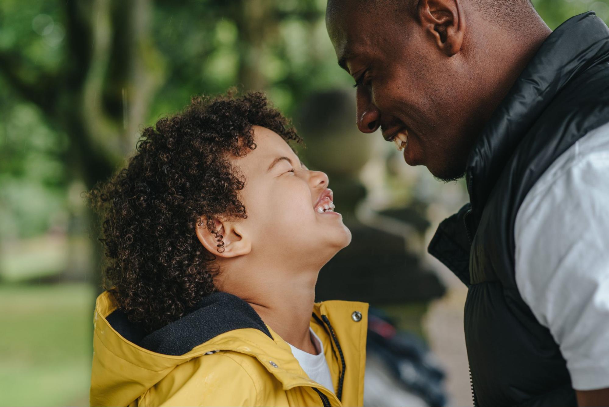 Young son smiling at father outside in park