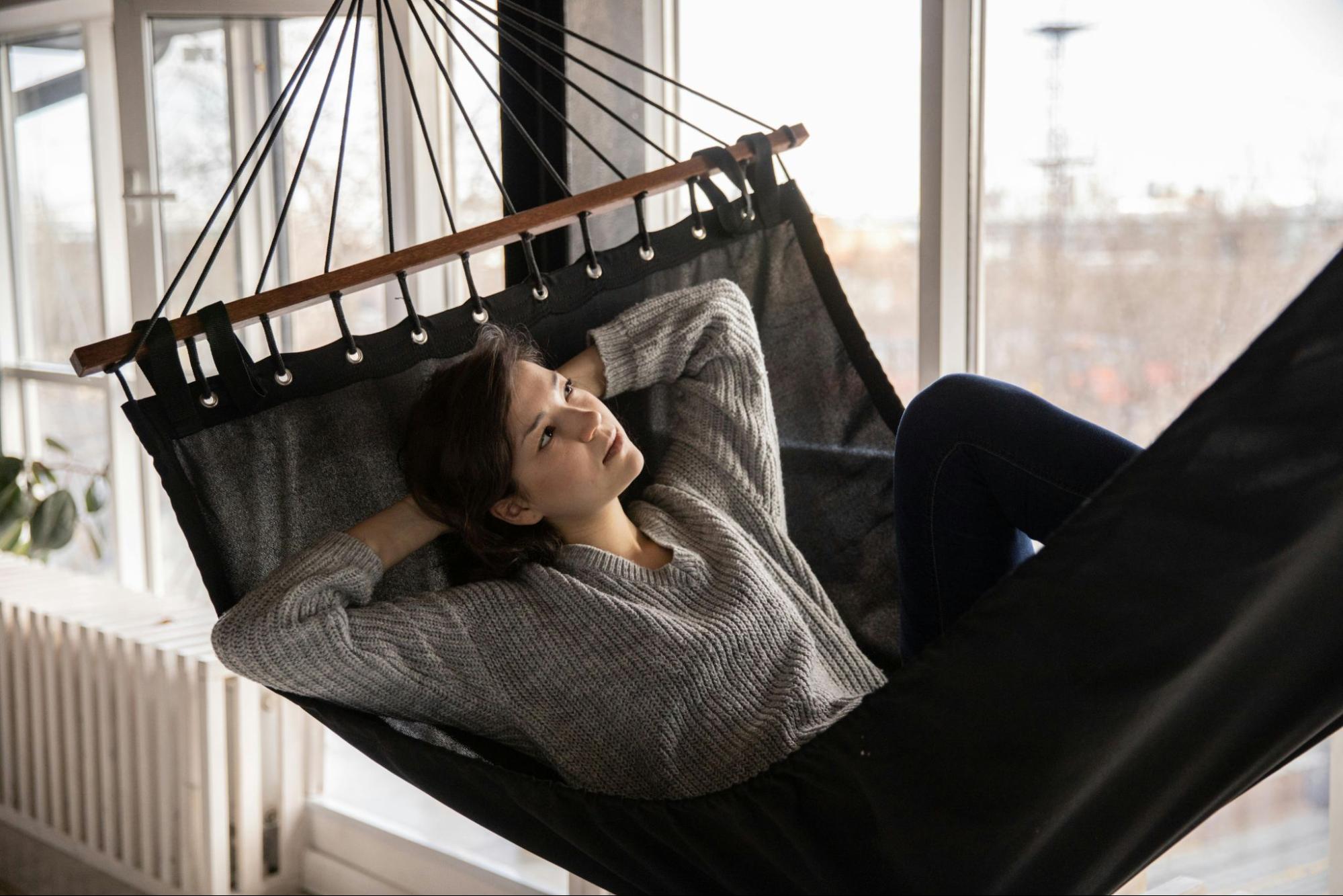 Woman sitting in hammock and looking outside