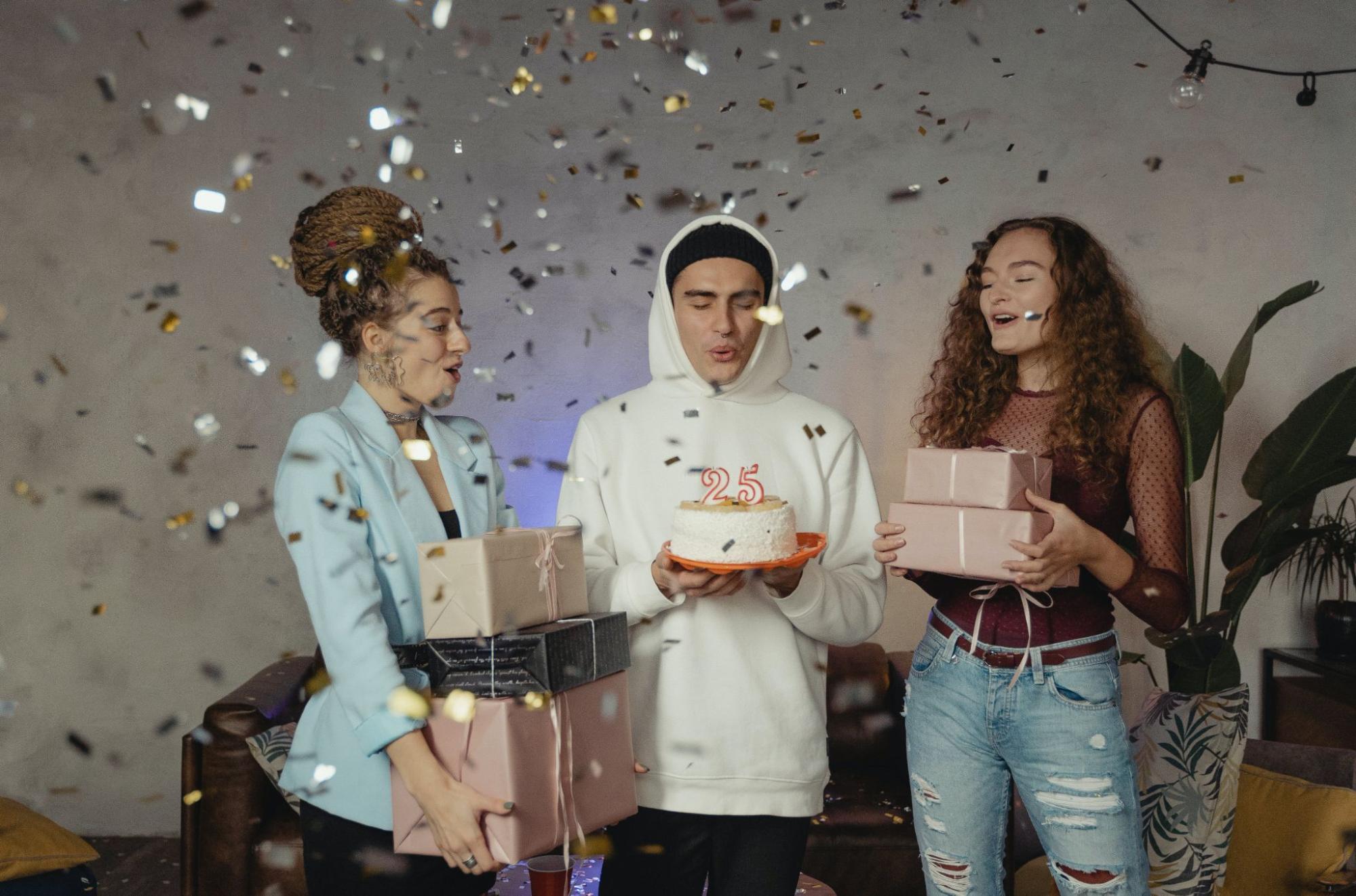 Person holding cake with friends and confetti