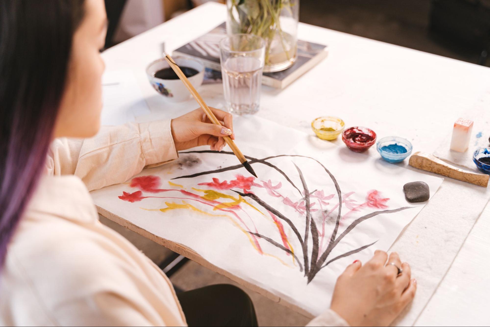 Person using paintbrush to paint on canvas