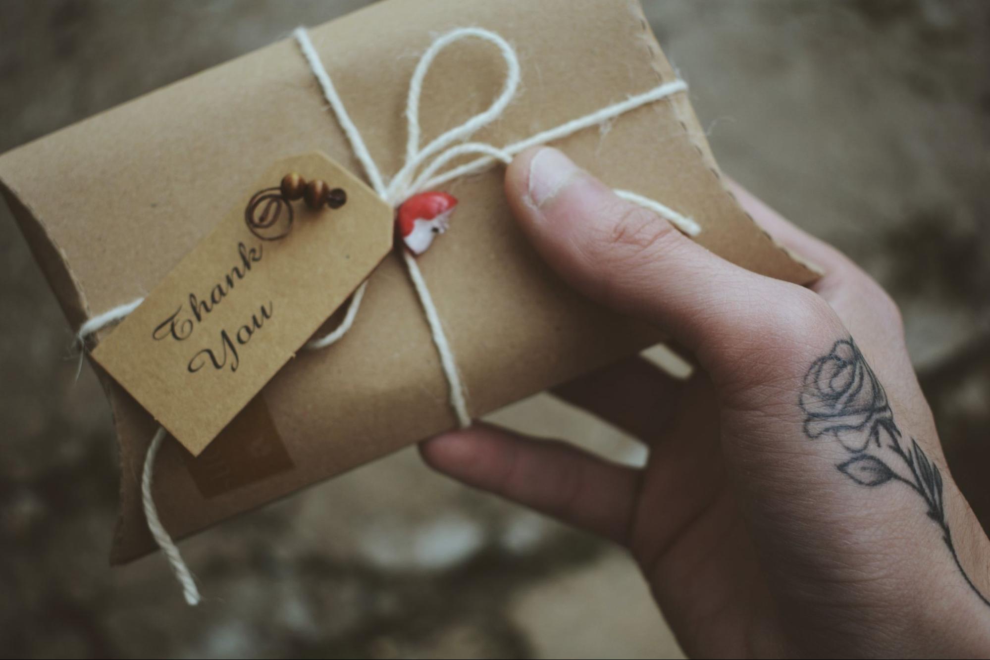 Person handing wrapped retirement gift card in paper envelope