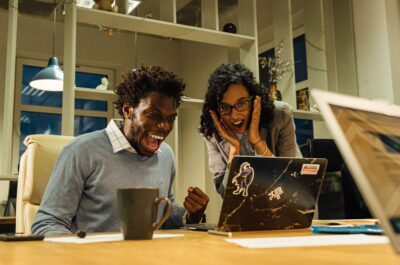 Employees smiling and excited looking at laptop