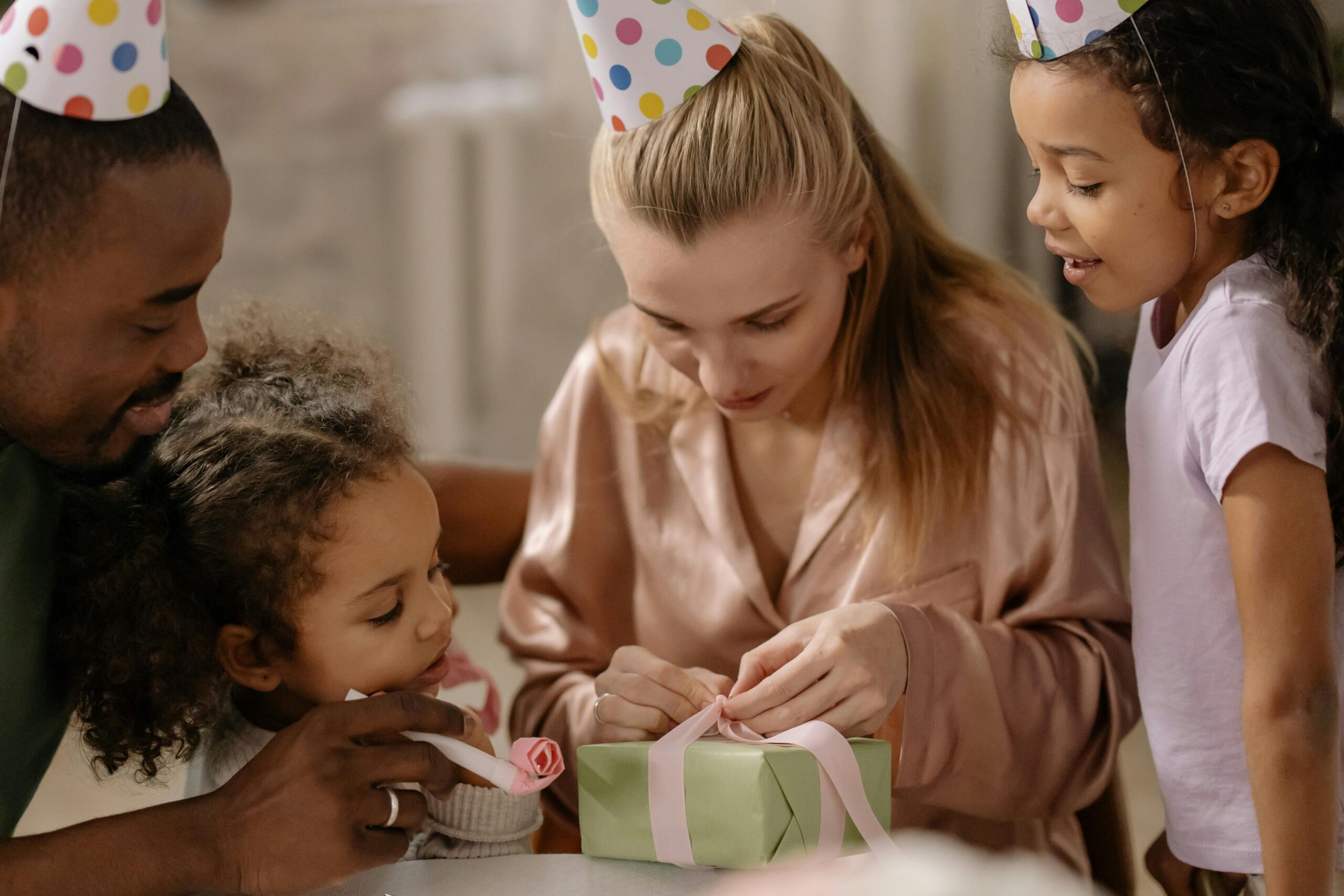 Mom opening presents with family wearing party hat