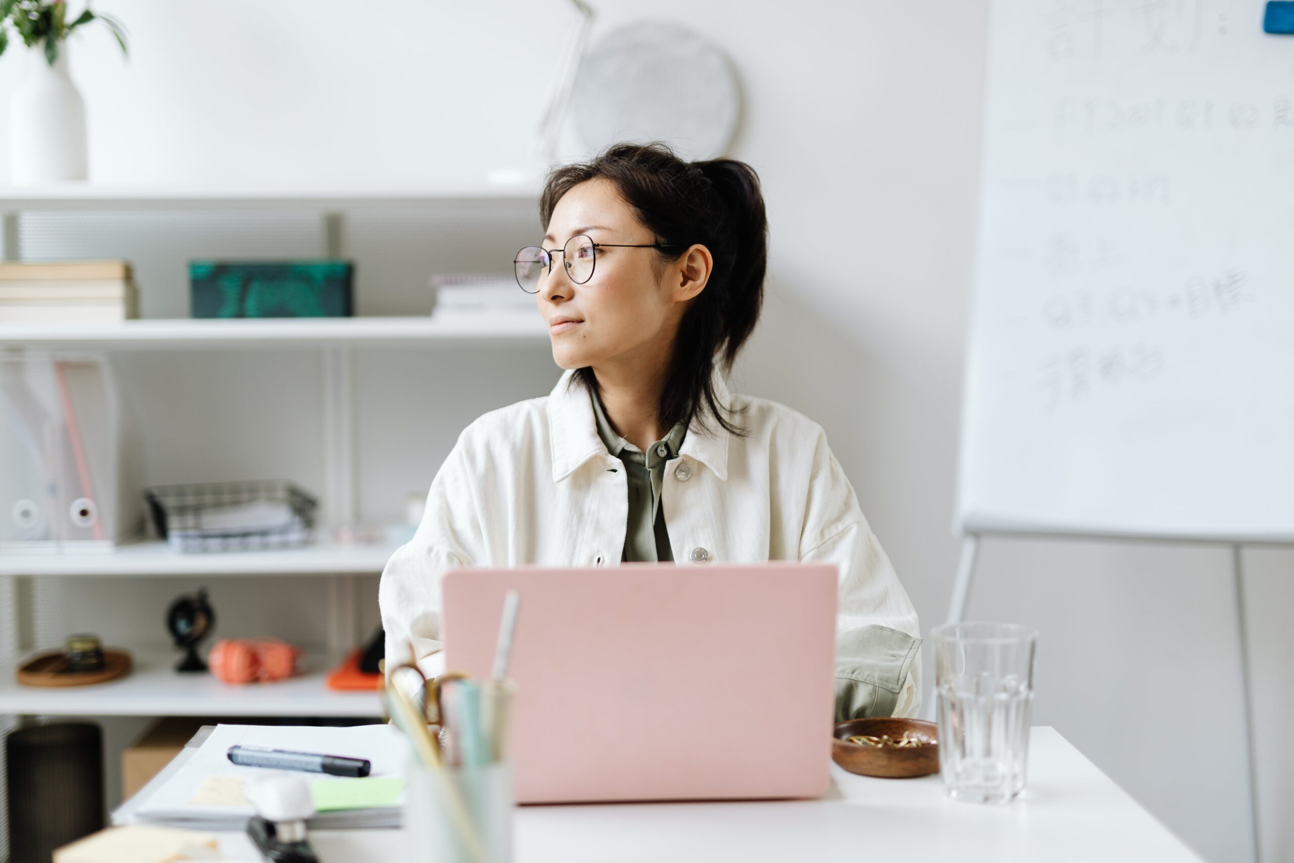 Employee working on laptop in office and looking out window