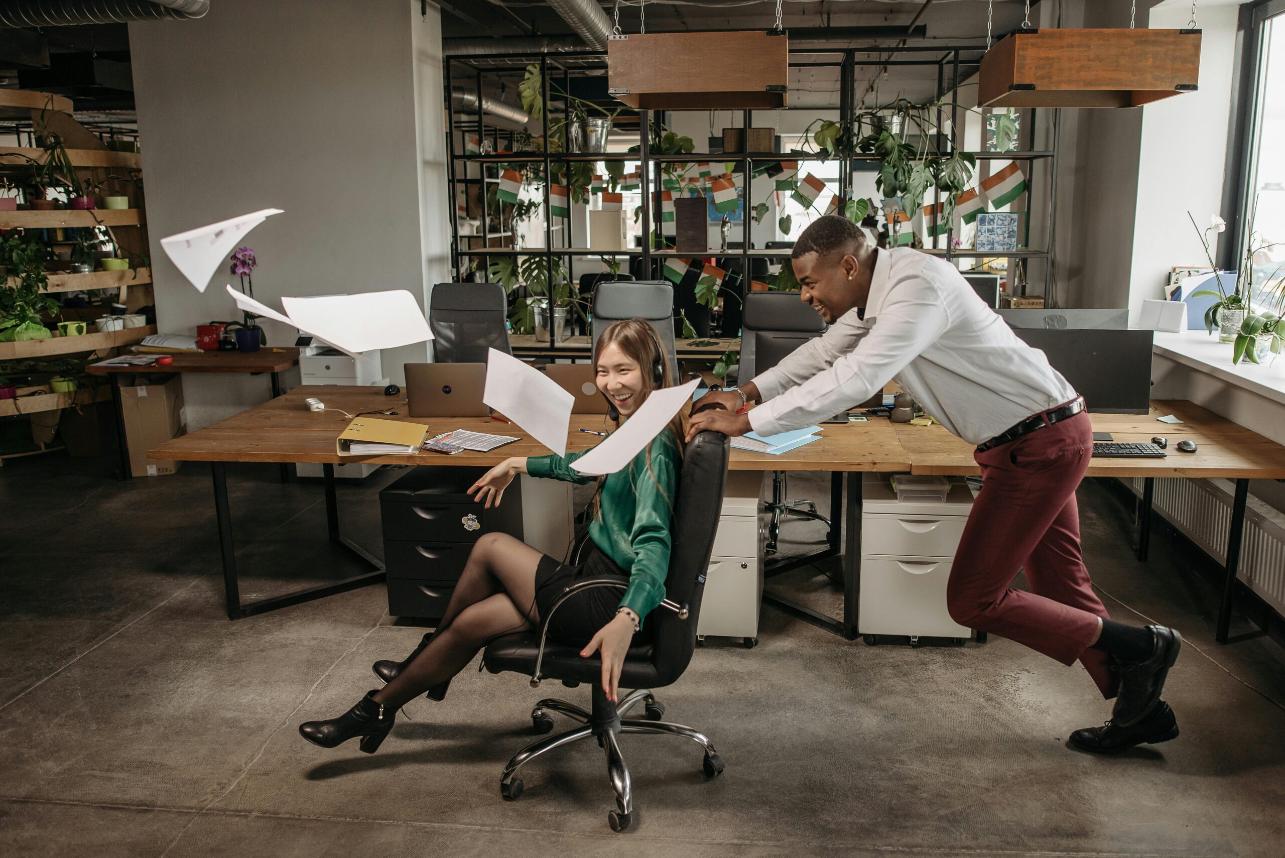 Employees having fun in the office by rolling around in chair