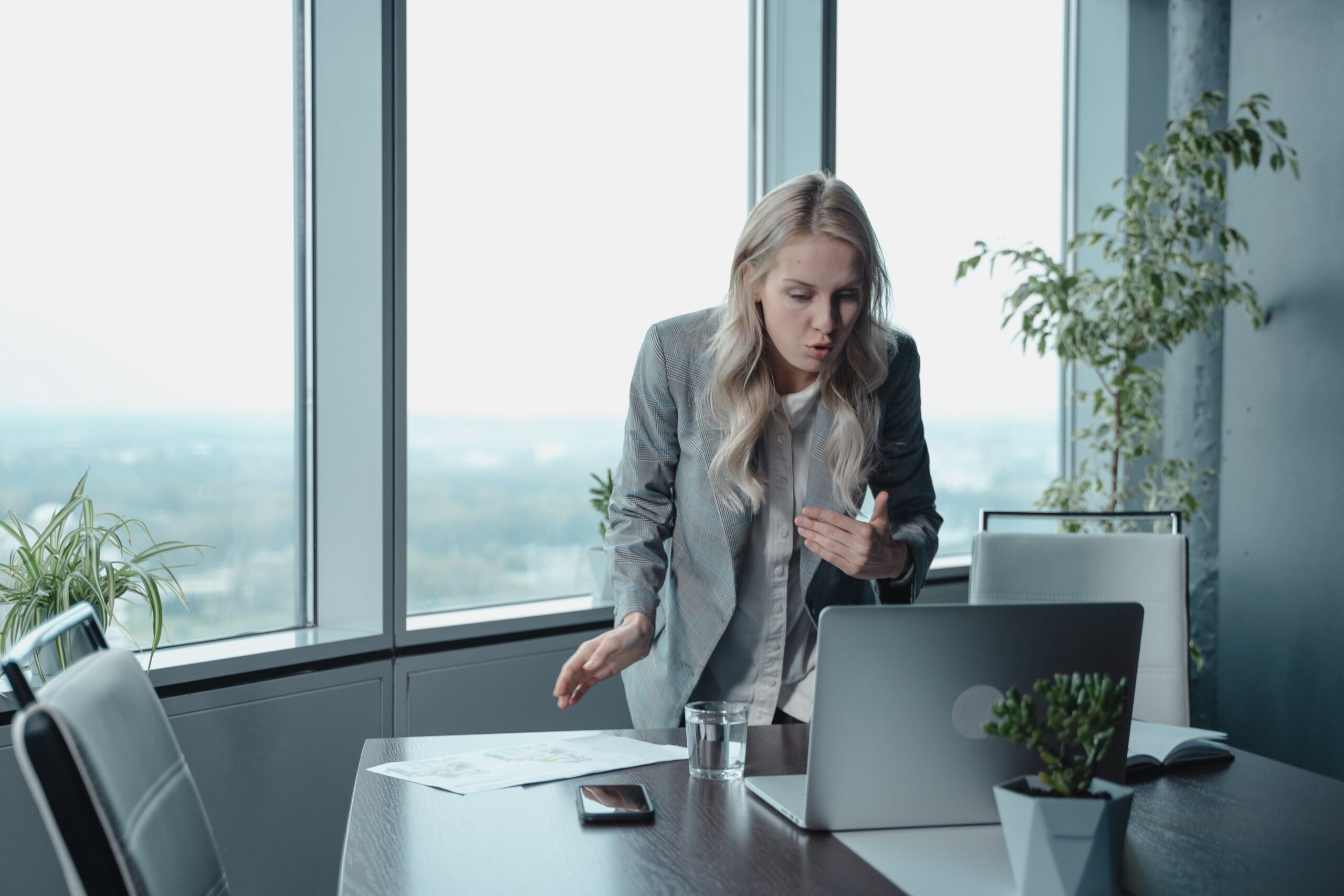 Woman talking with employees on laptop in office building