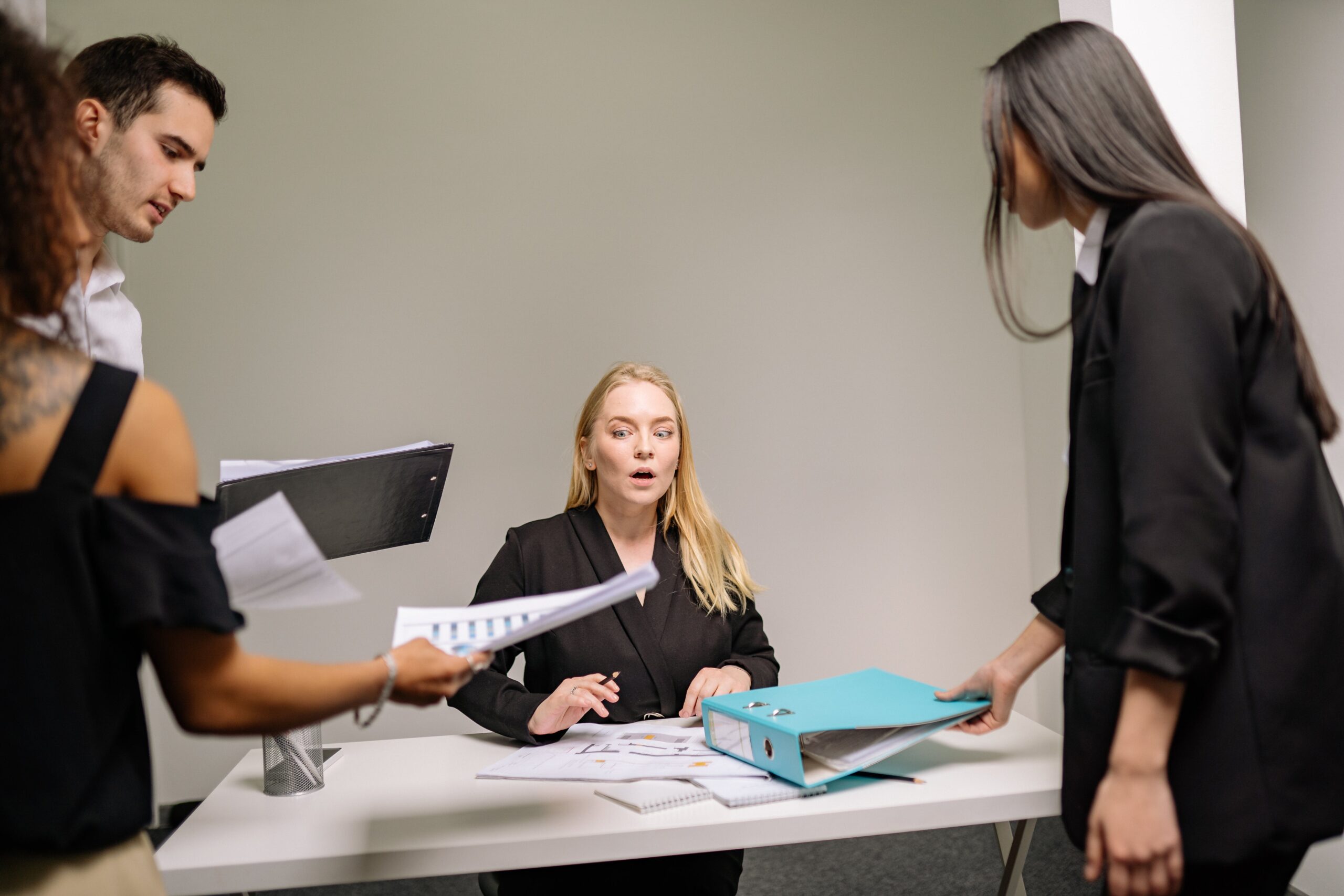 woman with people placing files and folders on her desk