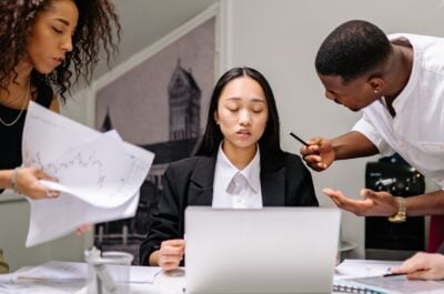 Employee at desk being talked to by a bunch of different employees at once