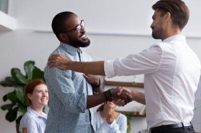 Manager shaking hands with employee during reward event