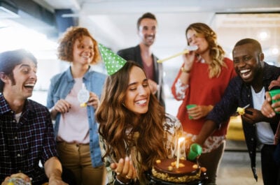 Female employee celebrating birthday in office with colleagues