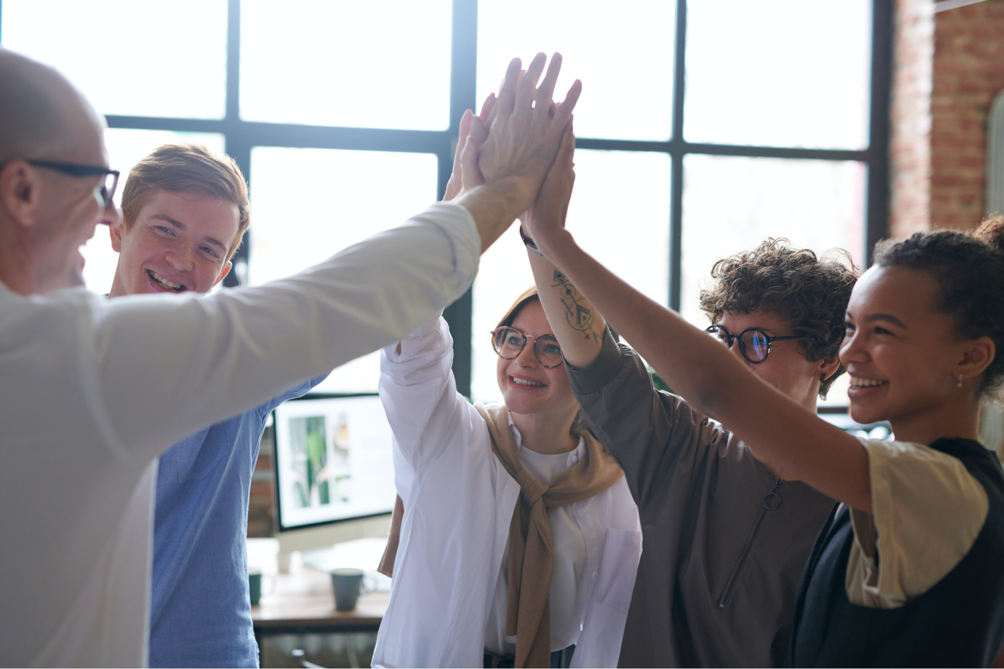 Team high five-ing in the office for an employee recognition award