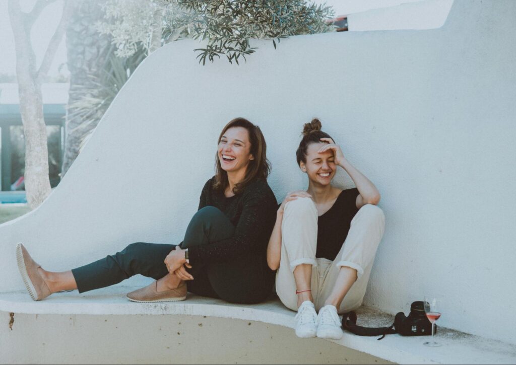 Two friends sitting together and laughing on a bench