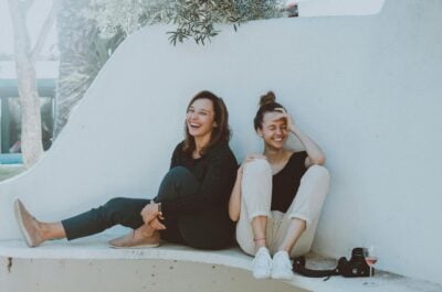 Two friends sitting together and laughing on a bench