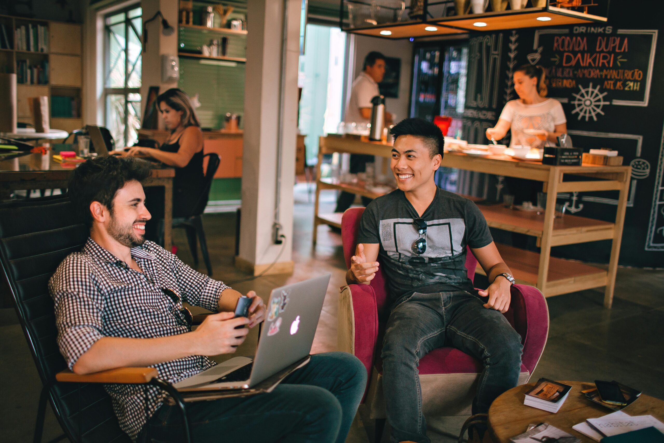 Two friends laughing and talking over laptops