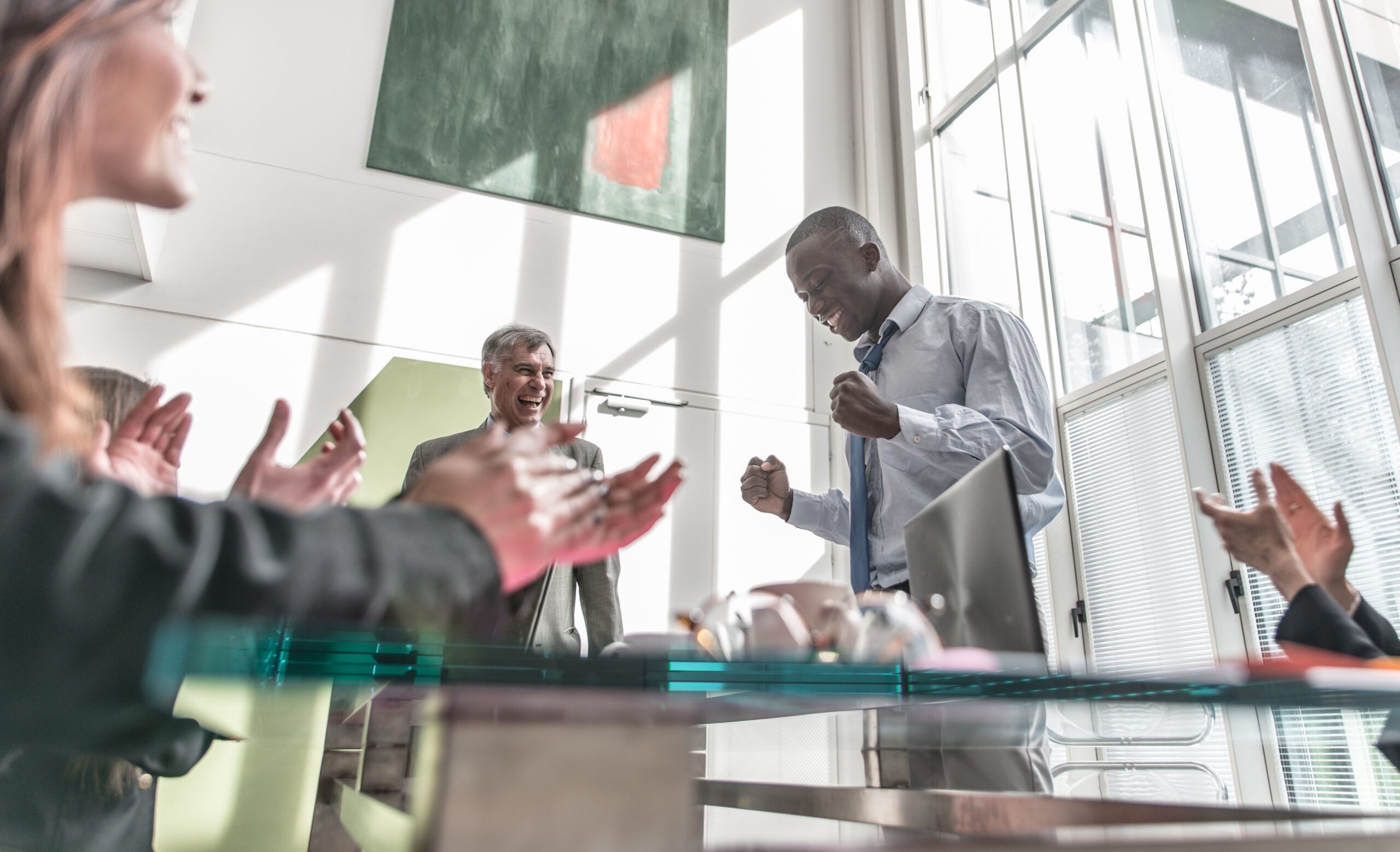 Man celebrating promotion while employees celebrate